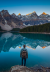 a person hiking at moraine lake, with the mountains reflecting off the calm, blue water