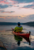 A kayaker resting on a lake during a beautiful sunset.